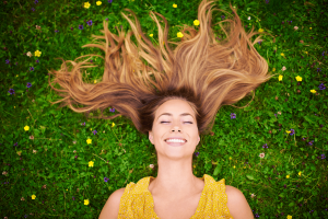 Women with long hair lying on bright green grass, communicating spring happiness after having detox treatment at Ballen Medical & Wellness